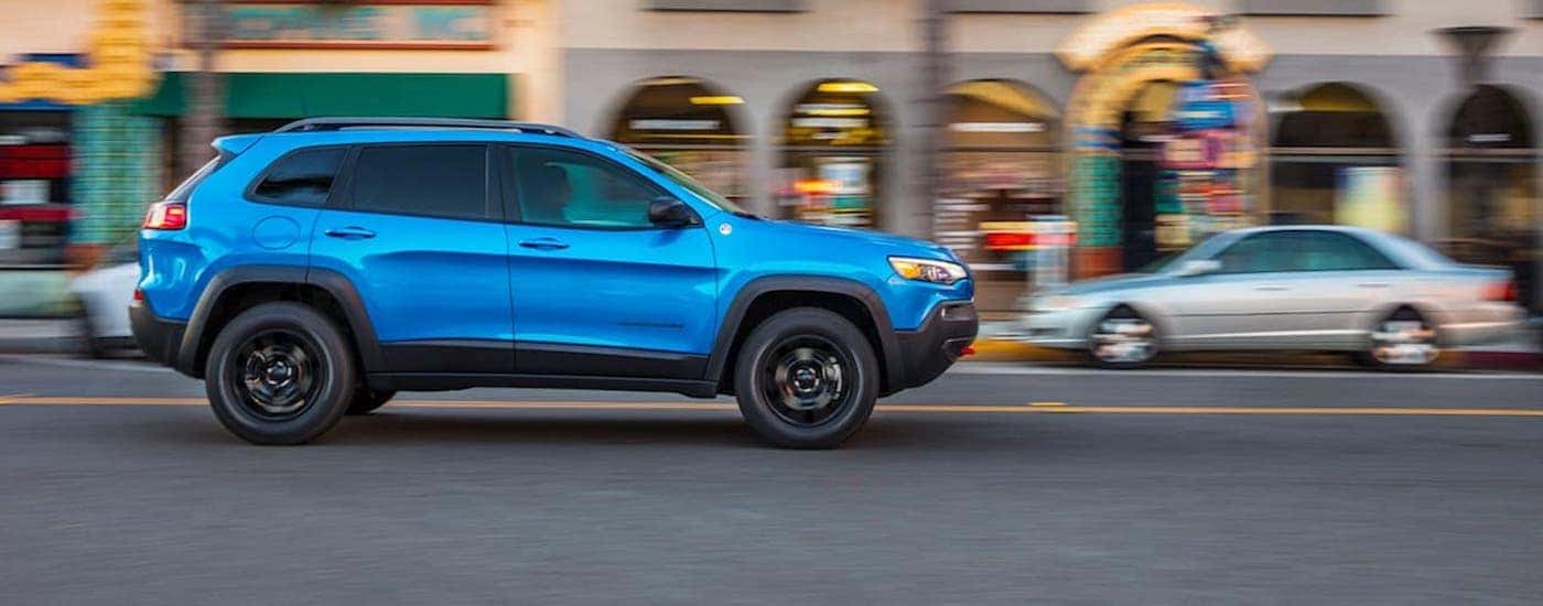 A blue 2020 Jeep Cherokee is shown from the side on a city street.
