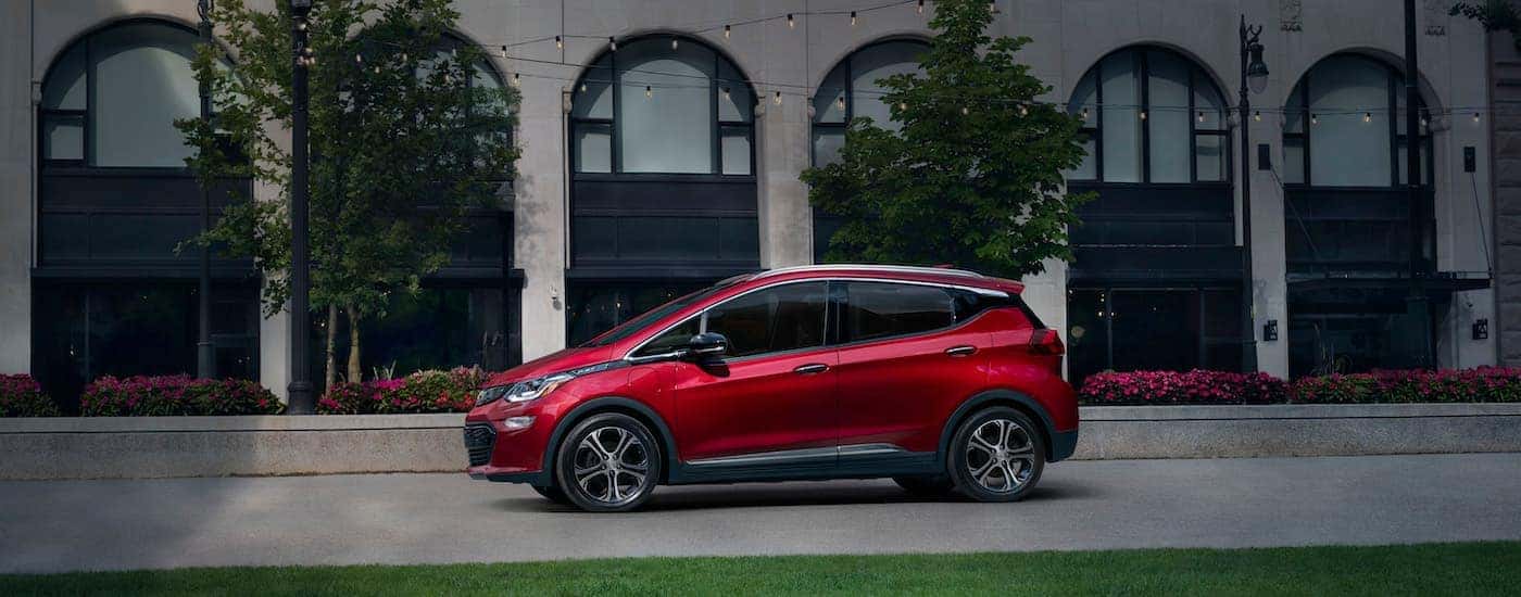 A red 2020 Chevy Bolt is shown from the side on a city street.