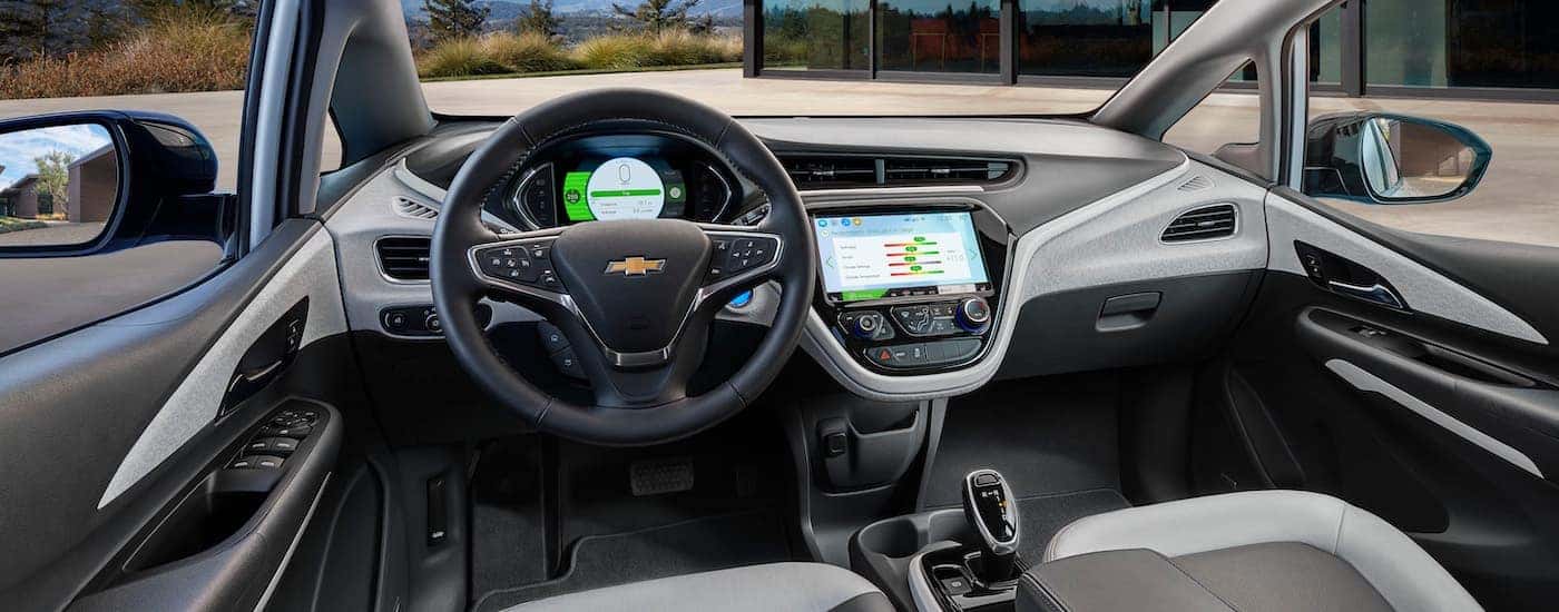The grey interior of a 2020 Chevy Bolt Ev is shown from the driver's seat.