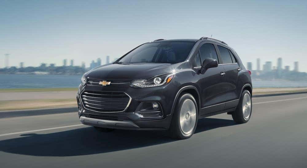 A black 2020 Chevy Trax for sale is shown driving near a city.