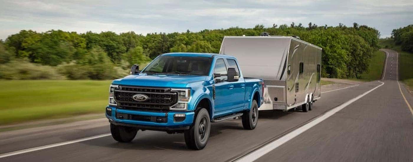 A blue 2020 Ford F-250 Tremor is shown from the front at an angle while towing a trailer.