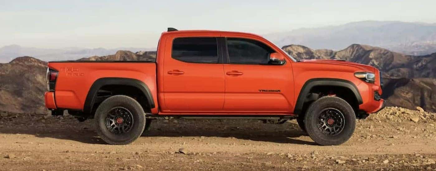 An orange 2023 Toyota Tacoma TRD is shown parked off-road.