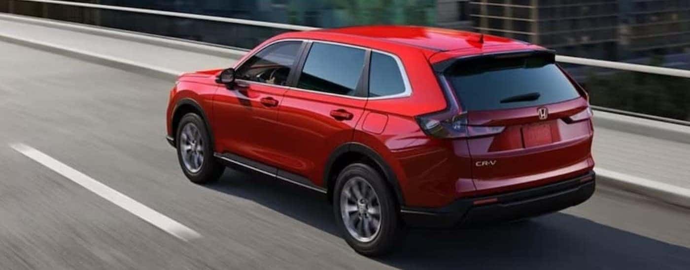 A red 2024 Honda CR-V is shown driving on a bridge.