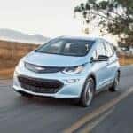 A light blue 2017 Chevy Bolt EV is shown from the front at an angle after leaving a dealer that has a used Chevy Bolt EV for sale.