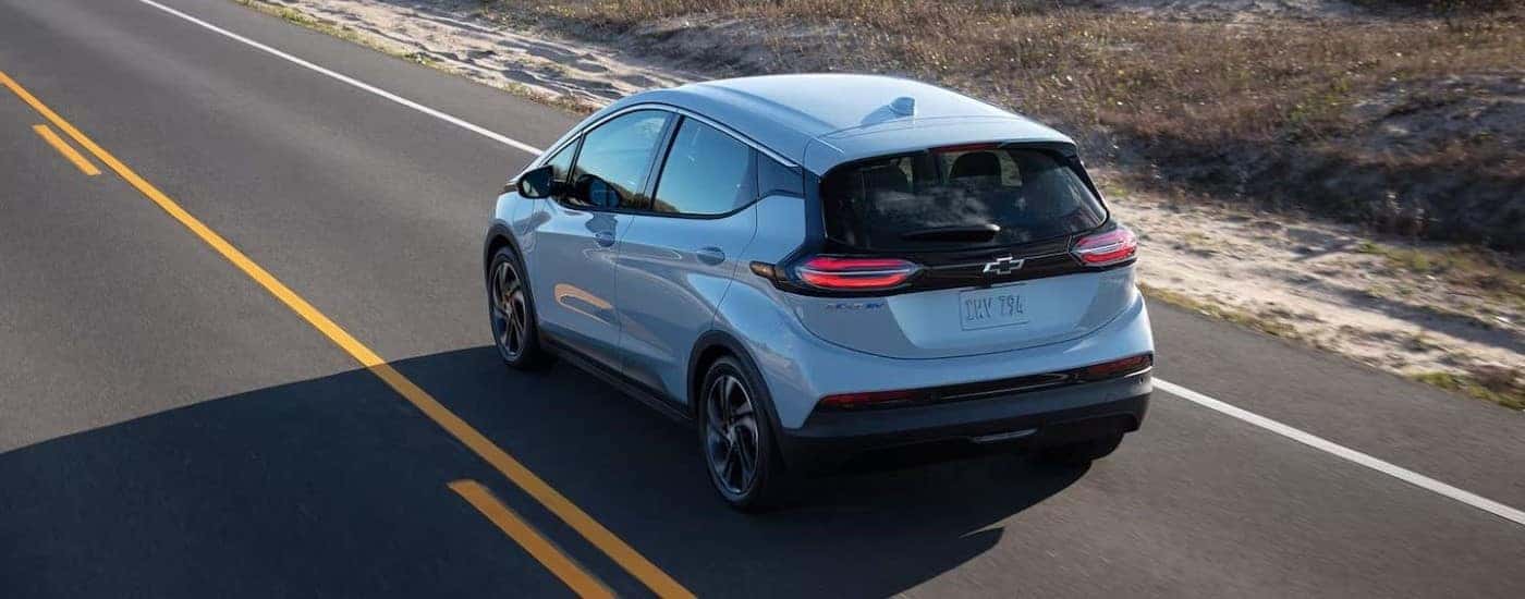 A light blue 2022 Chevy Bolt EV is shown driving on an open road.