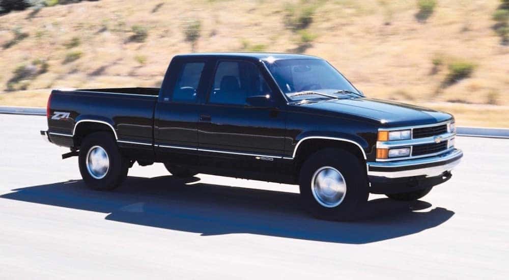 A black 1999 Chevy Silverado 1500 is shown driving on a highway.