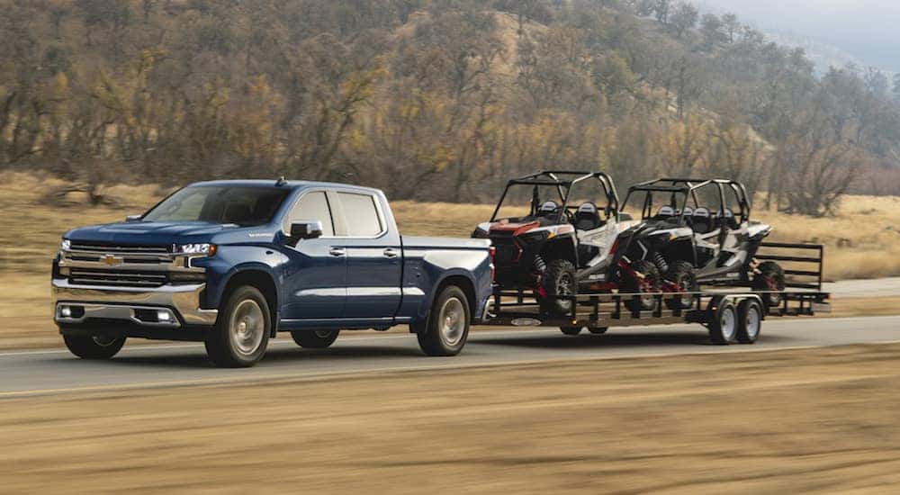A blue 2021 Chevy silverado 1500 is shown towing a trailer.