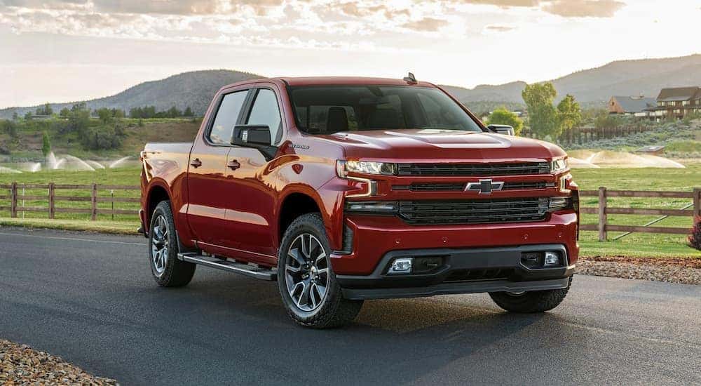 A red 2021 Chevy Silverado 1500 for sale is shown parked near a wooden fence.