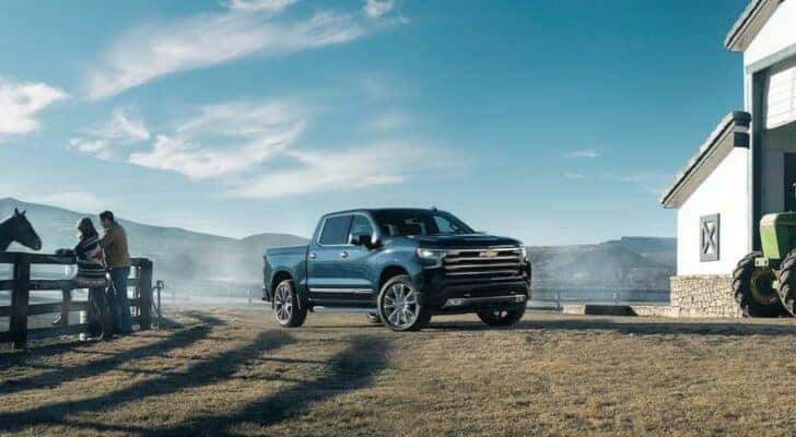 A popular Chevy Silverado 1500 for sale, a blue 2023 Chevy Silverado 1500 LT, is shown parked near a barn.