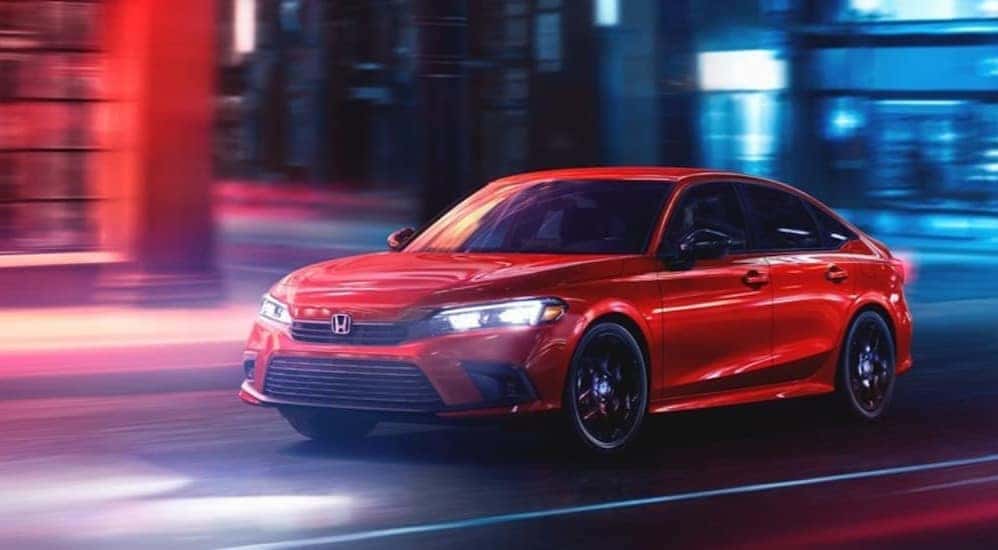 A red 2023 Honda Civic Sport is shown driving to Charleston, WV car sales.