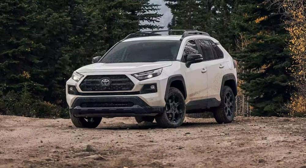 Great for Charleston, WV SUV sales, a white 2023 Toyota RAV4, is shown parked off-road.
