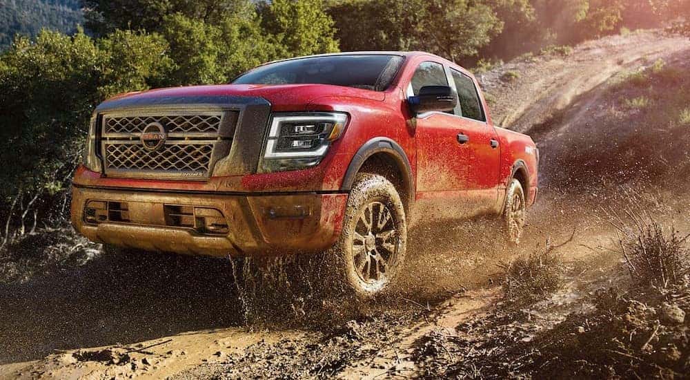 A red 2023 Nissan Titan Pro 4X is shown driving off-road.