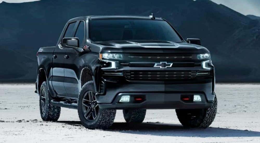 A popular truck at Charleston, WV truck sales, a black 2024 Chevy Silverado 1500 LT Trailboss Midnight Edition, is shown parked off-road.