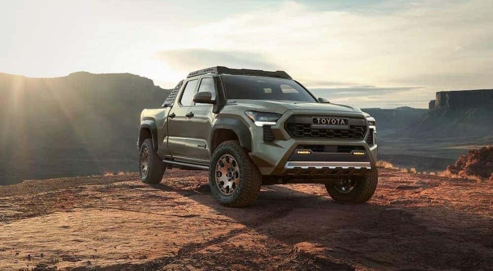 A green 2024 Toyota Tacoma is shown parked near a cliff.