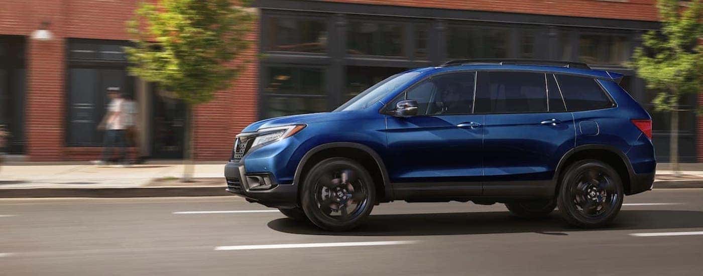 A blue 2021 Honda Passport Elite is shown from the side on a city street.