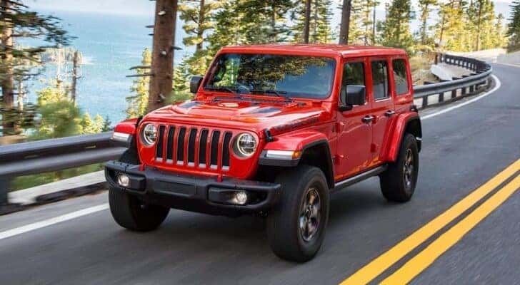 A popular used Jeep Wrangler for sale, a red 2021 Jeep Wrangler Rubicon, is shown driving on a highway.