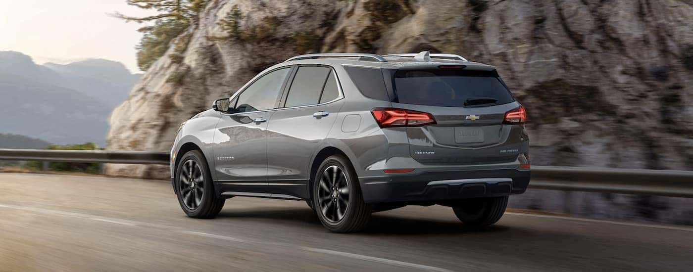 A gray 2023 Chevy Equinox LT is shown driving near a guardrail.
