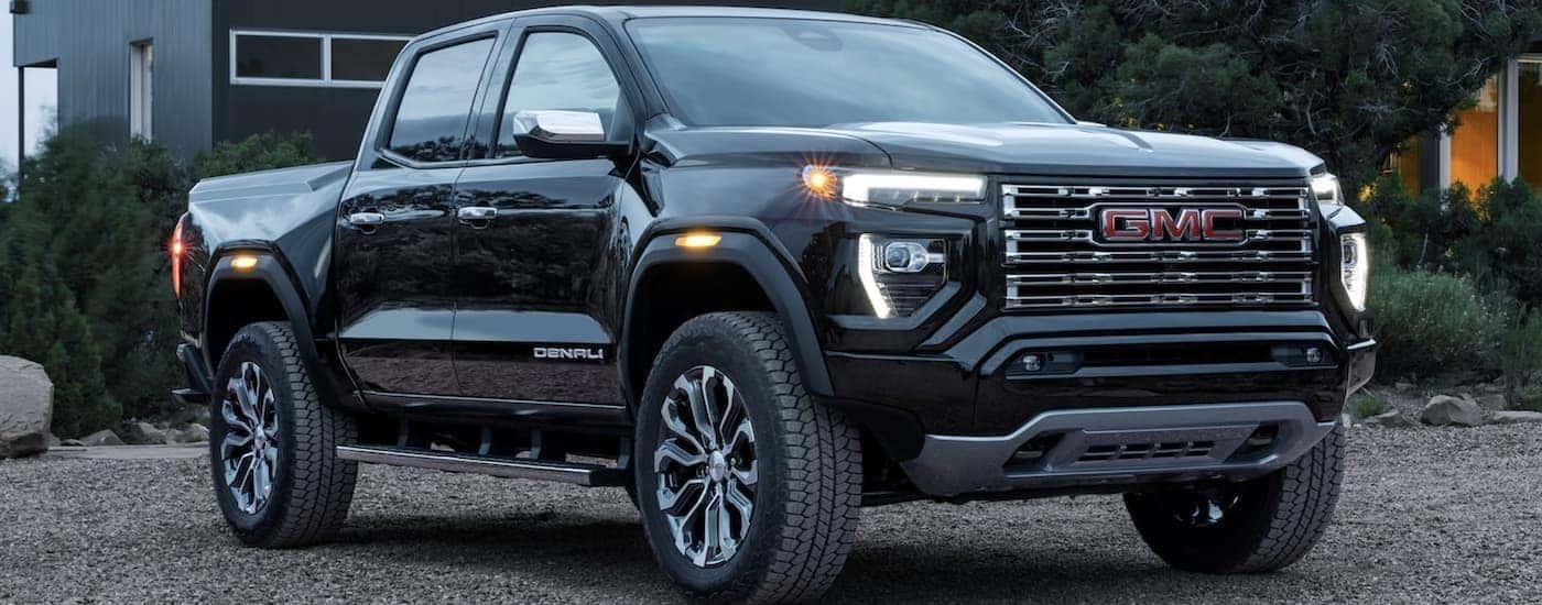 A black 2023 GMC Canyon Denali is shown parked near a house.