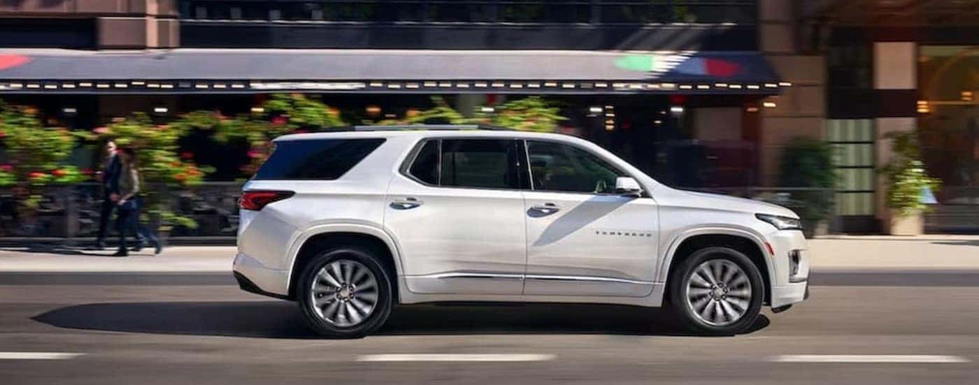 A white 2023 Chevy Traverse is shown driving on a city street.