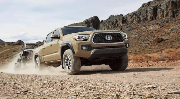 A tan 2019 Toyota Tacoma is shown towing a trailer after viewing Dayton truck sales.