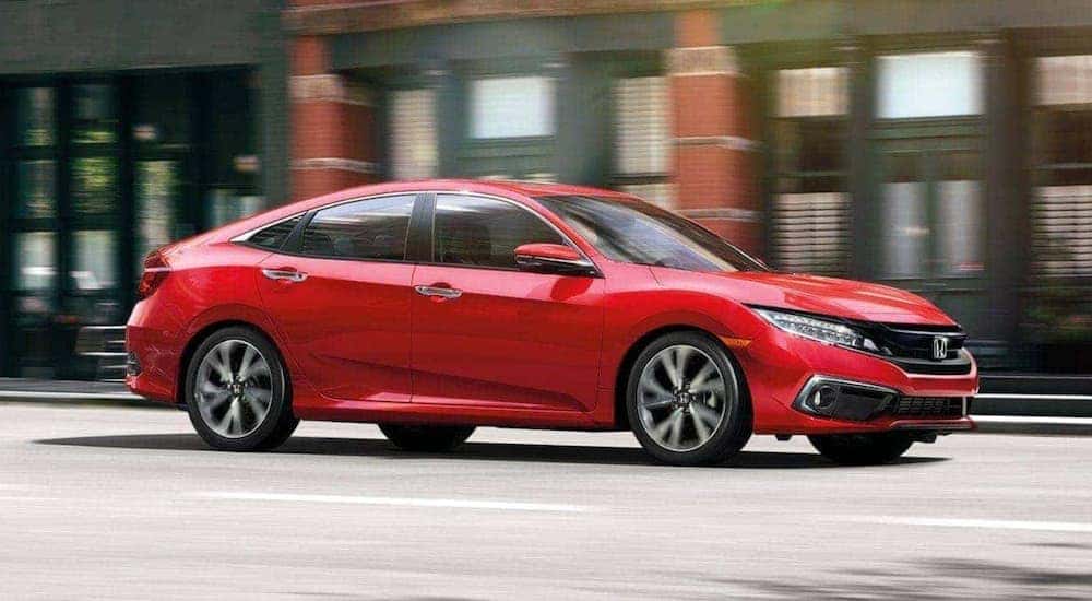 A red 2020 Honda Civic is shown from the side on a city street.