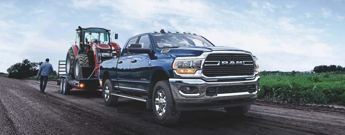 A blue 2021 Ram 2500 is shown towing a trailer off-road.