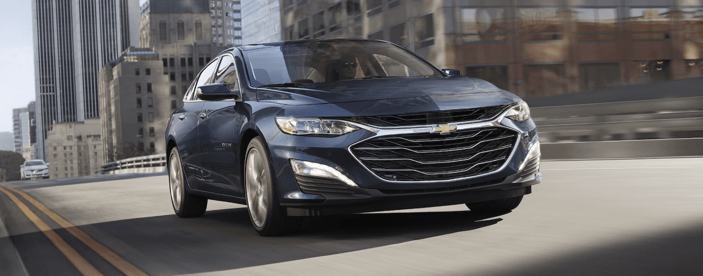 A blue 2022 Chevy Malibu is shown driving on a city street.