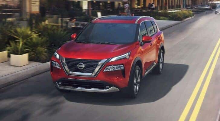A red 2023 Nissan Rogue is shown driving on a highway after viewing Dayton SUV sales.