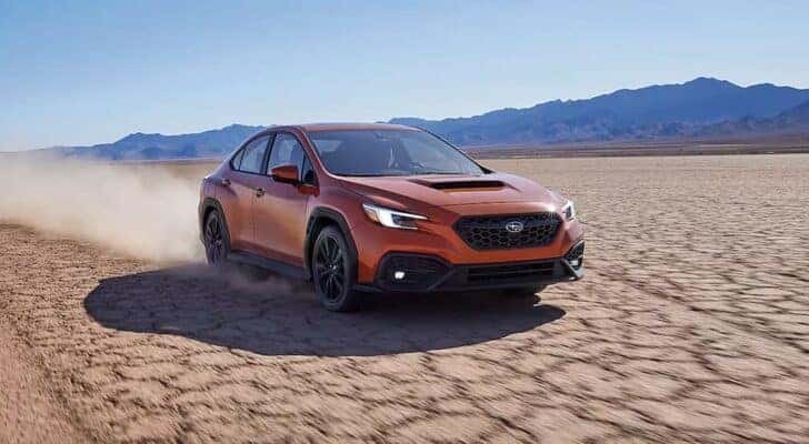 An orange 2023 Subaru WRX is shown driving off-road after searching Dayton car sales.