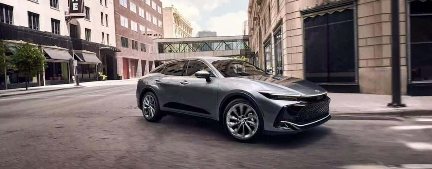 A silver 2023 Toyota Crown is shown driving in a city.