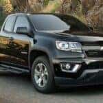 A popular used Chevy Colorado for sale, a black 2020 Chevy Colorado Z71, is shown driving on a highway.
