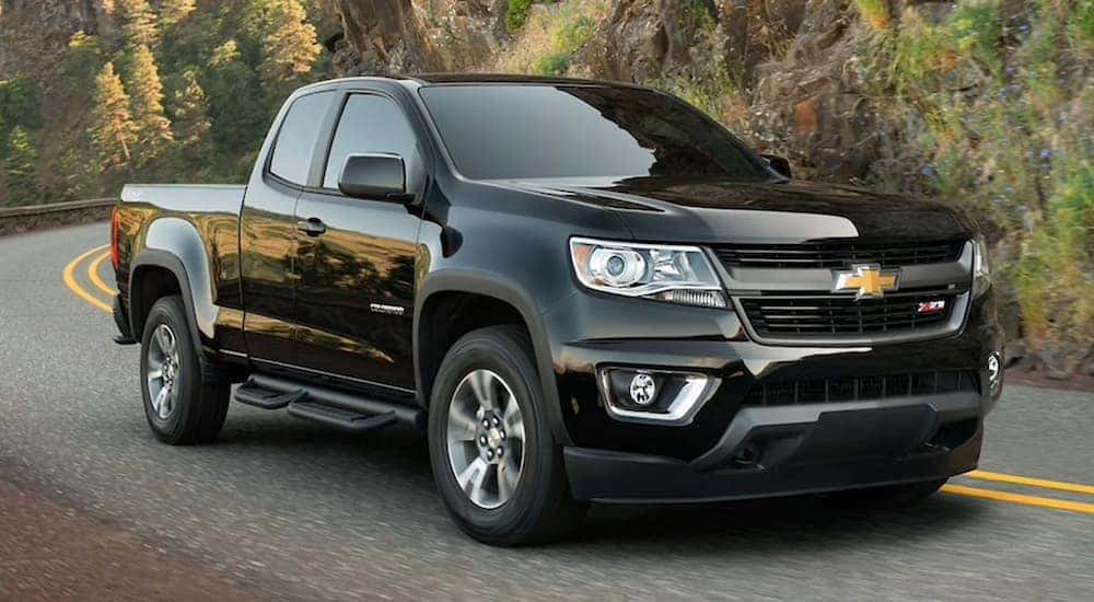 A popular used Chevy Colorado for sale, a black 2020 Chevy Colorado Z71, is shown driving on a highway.