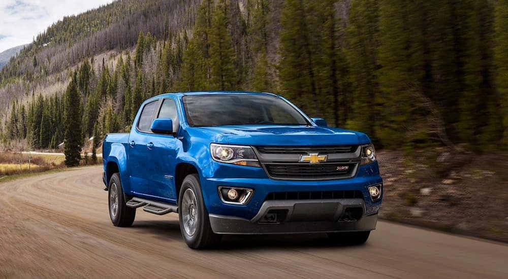 A blue 2020 Chevy Colorado Z71 is shown driving on a dirt road.