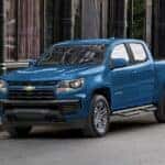 A blue 2022 Chevy Colorado for sale is shown parked near a city curb.