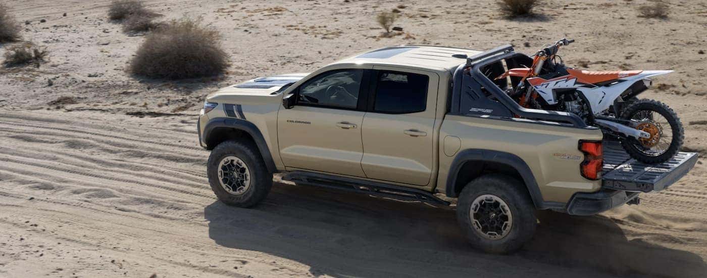 A tan 2023 Chevy Colorado ZR2 Desert Boss is shown driving in a desert.