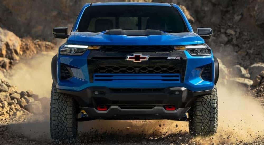 A popular Chevy Colorado for sale, a blue 2024 Chevy Colorado ZR2, is shown driving off-road.