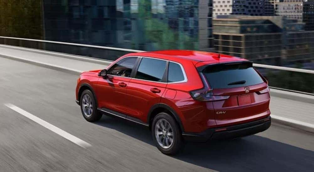 A red 2024 Honda CR-V is shown driving on a bridge.
