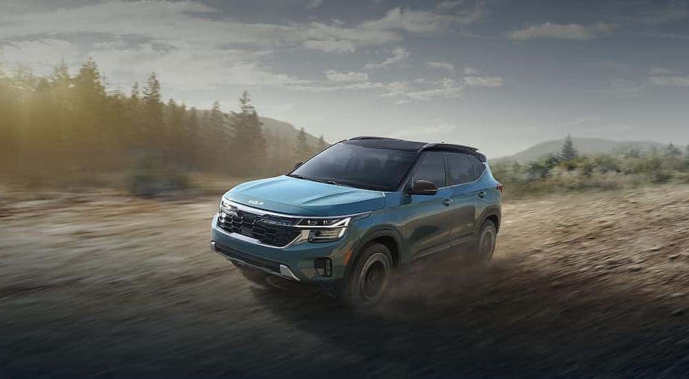 A green 2024 Kia Seltos is shown driving off-road.