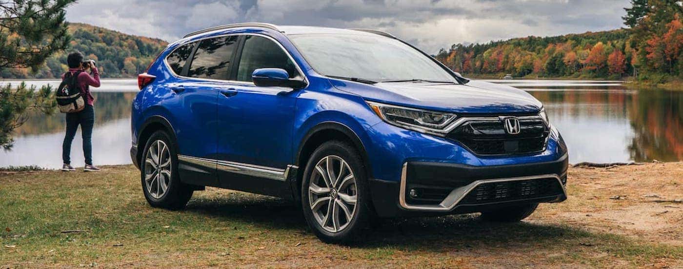 A blue 2022 Honda CR-V Touring is shown parked by a lake.