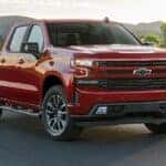 A red 2021 Chevy Silverado 1500 Diesel is shown driving from some Columbus truck sales.