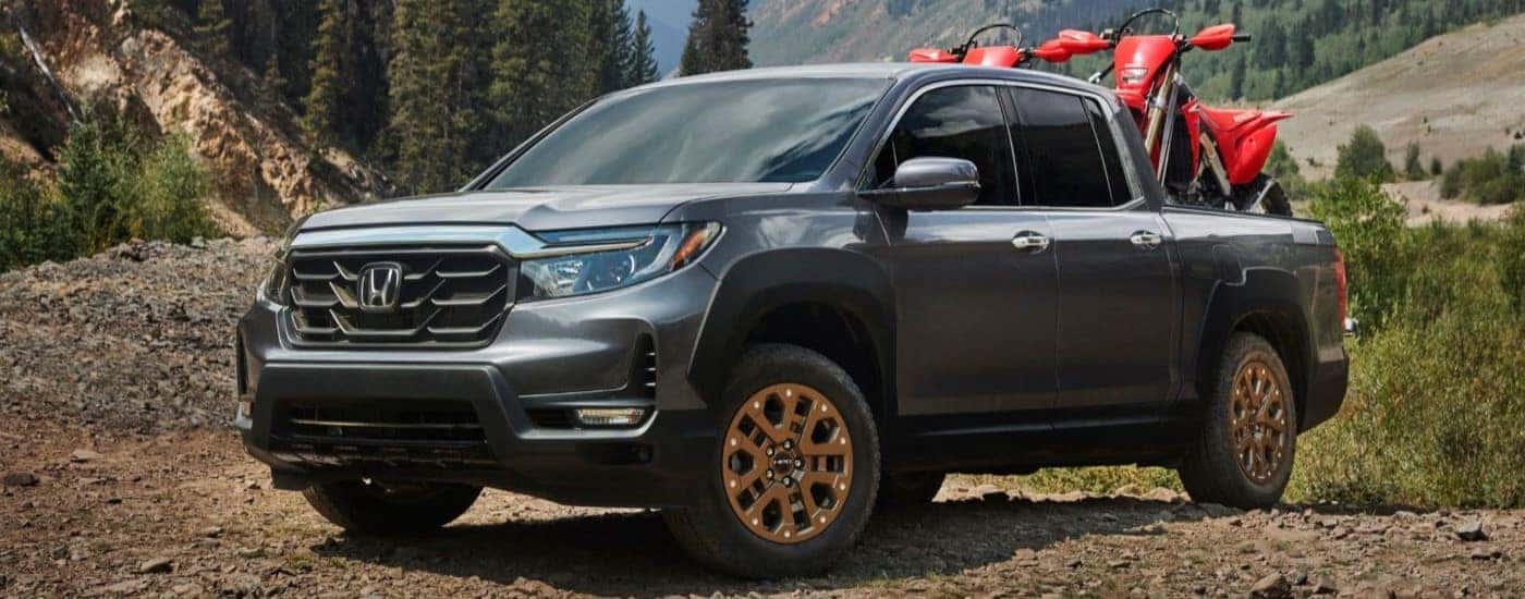 A black 2021 Honda Ridgeline is shown parked off-road while hauling a set of dirt bikes.