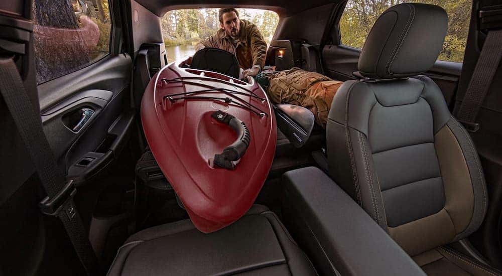 A person is shown placing his kayak into the cargo area of a 2021 Chevy Trailblazer.