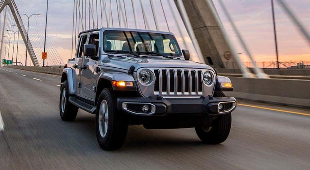 A silver 2021 Jeep Wrangler is shown driving on a bridge after viewing a Jeep Wrangler for sale in Louisville.