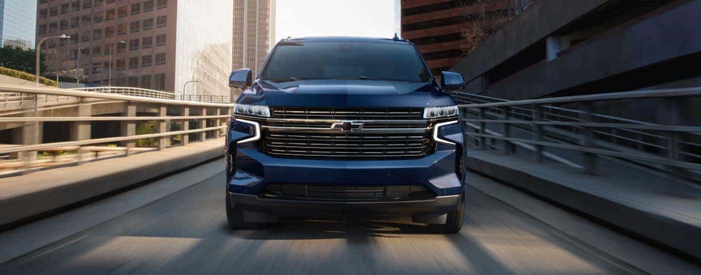 A blue 2023 Chevy Tahoe is shown driving on an off-ramp.