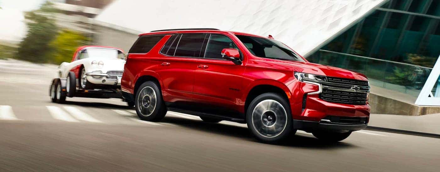 A red 2023 Chevy Tahoe for sale is shown towing a trailer.
