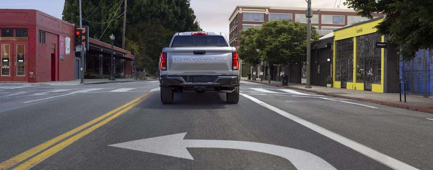A silver 2023 Chevy Colorado Z71 is shown from the rear on a city street.