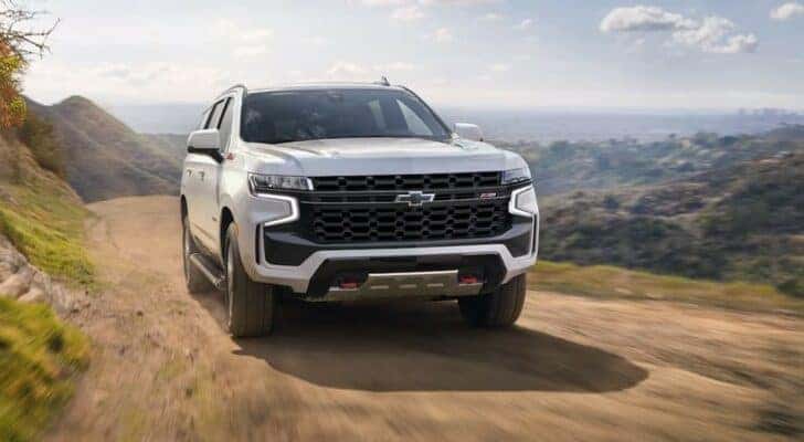 A white 2023 Chevy Tahoe Z71 is shown driving off-road.