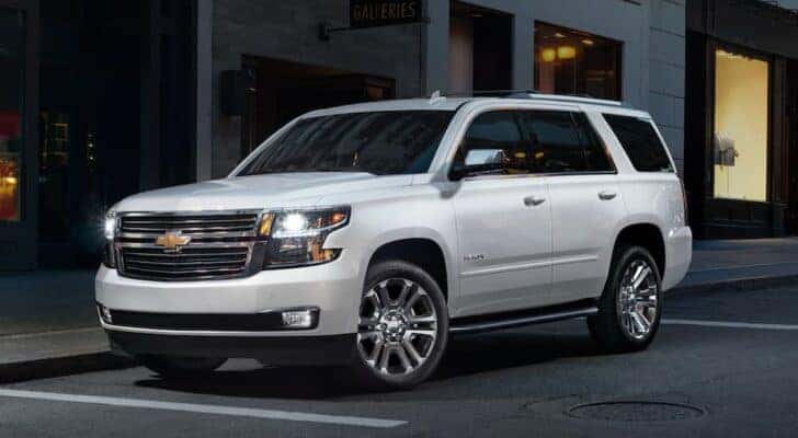 A white 2020 Chevy Tahoe is shown driving on a city street to view a used Chevy Tahoe for sale.