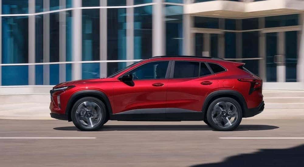 A red 2024 Chevy Trax RS is shown driving on a city street.