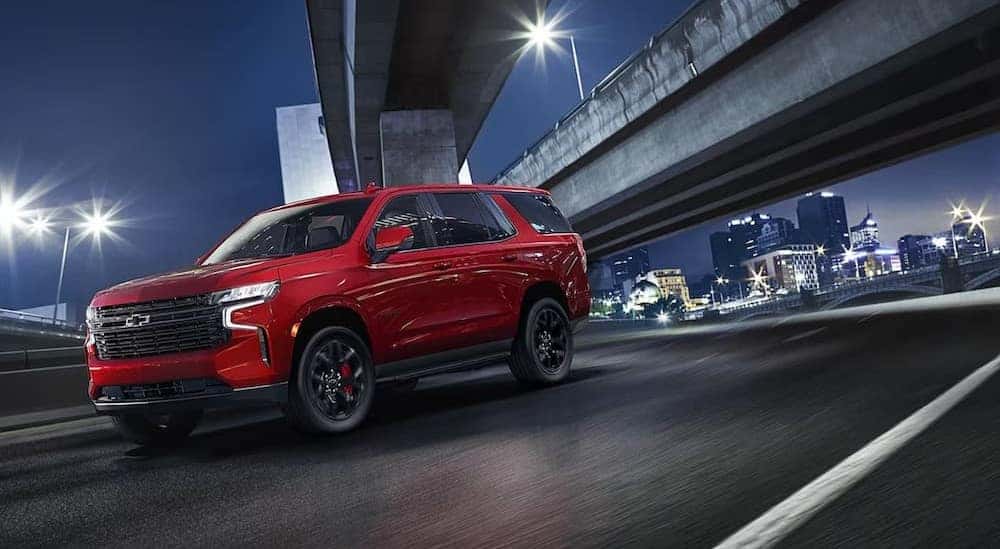 A red 2023 Chevy Tahoe is shown driving near a city.